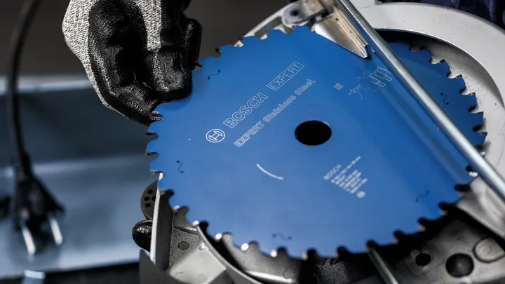 Een persoon die veiligheidsuitrusting draagt, monteert een cirkelzaagblad in een elektrisch gereedschap.