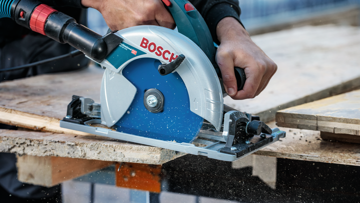 Persoon die een cirkelzaag bedient om hout te zagen op een werkbank.