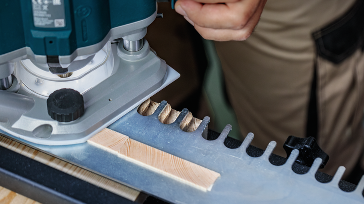 Een persoon gebruikt een bovenfrees om nauwkeurige groeven in een houten plank te frezen.