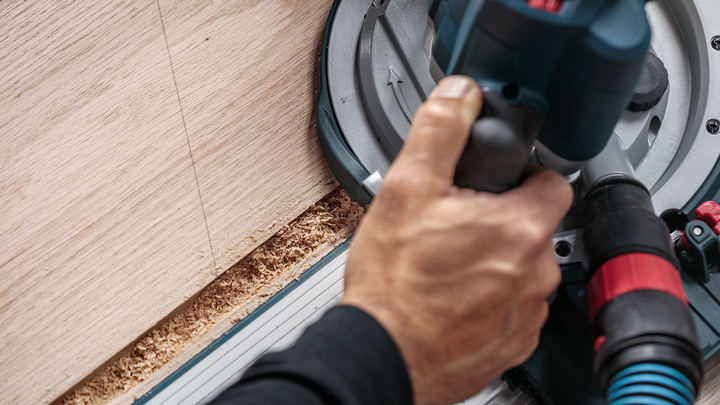 Persoon bedient een cirkelzaag om hout in een rechte lijn te zagen.