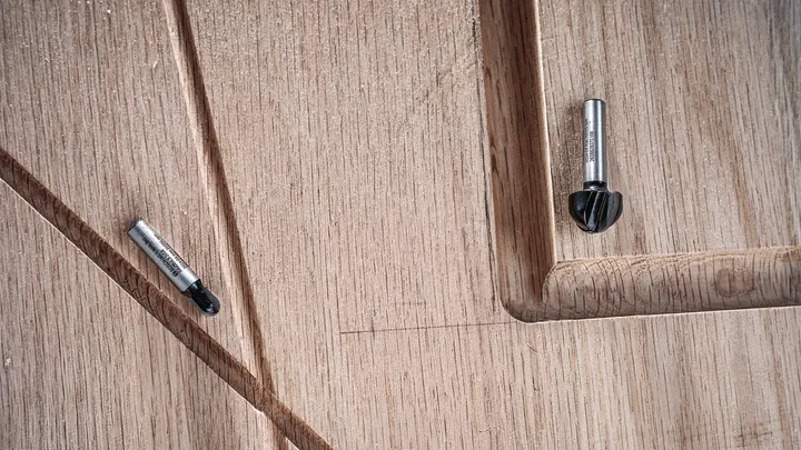 Twee freesbits rusten op een bewerkt houten oppervlak met gegroefde details.