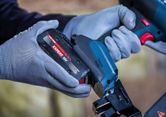 Een persoon die veiligheidsuitrusting draagt, plaatst een batterij in een snoerloze nietmachine.