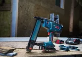 Draadloze kroonnietmachine van gemiddelde grootte, geplaatst op een houten werkbank met accu's in de buurt.