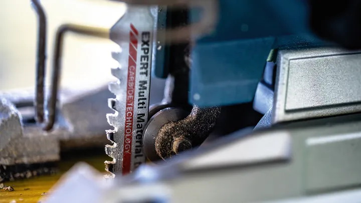 Close-up van een zaagblad voor meerdere materialen dat door hout zaagt.