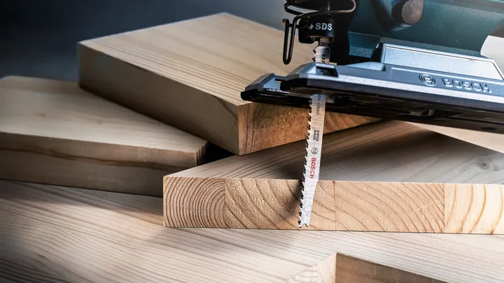 Een decoupeerzaag zaagt door een dikke houten plank.