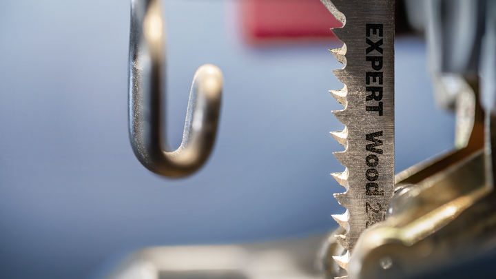 Close-up van een decoupeerzaagblad, voorzien van het label 'voor het zagen van hout', bevestigd aan een elektrisch gereedschap.