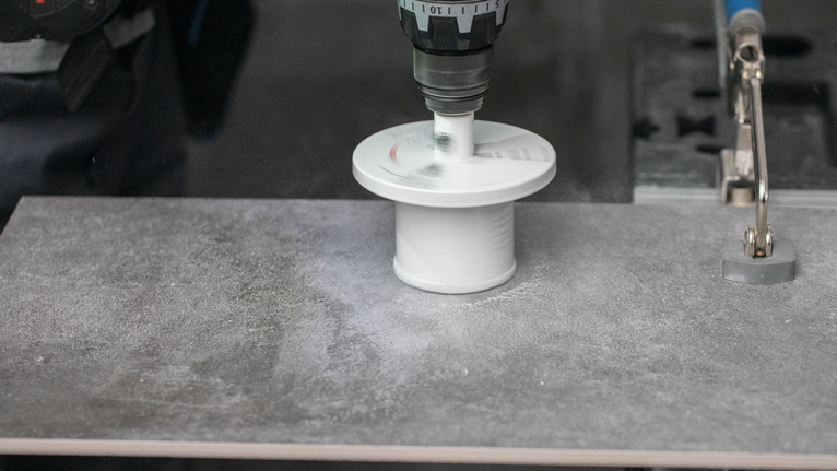 Boor met gatenzaagopzetstuk een ronde opening in een tegelplaat.