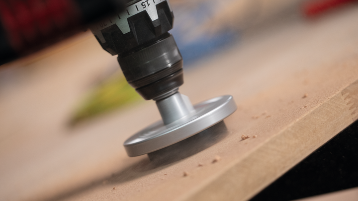Roterend gereedschap voor het schuren van de rand van een houten plank.