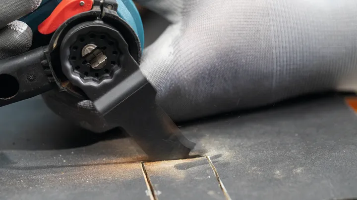 Een persoon die veiligheidsuitrusting draagt, gebruikt een elektrisch gereedschap om een groef in hout te maken.