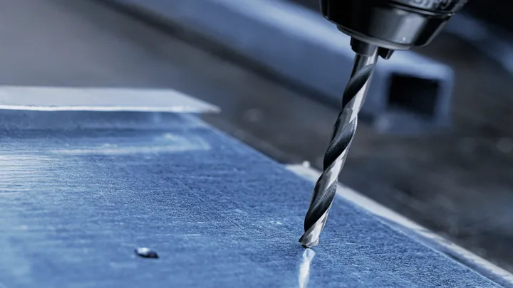 Boormachine die een gat in een metalen plaat maakt.