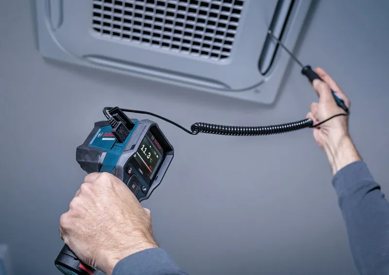 Iemand meet de luchttemperatuur bij een plafondventilator met behulp van een digitaal inspectie-instrument.