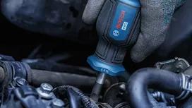 Een persoon die veiligheidsuitrusting draagt, gebruikt een schroevendraaier om aan motoronderdelen te werken.