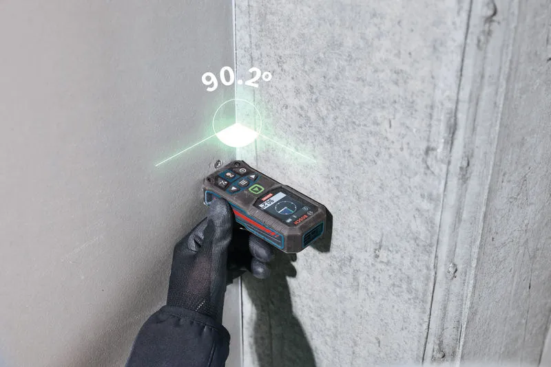 Een persoon die veiligheidsuitrusting draagt, gebruikt een lasermeetinstrument om een ​​hoek te controleren.