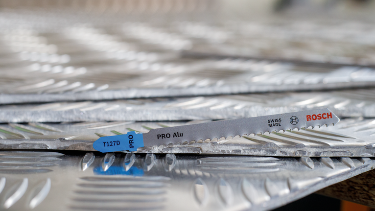 Ножче на трион, поставено върху подредени листове от текстуриран метал.