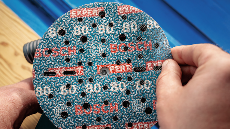 Човек, който прикрепя шлифовъчен диск към електрическа шлайфмашина.