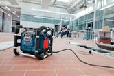 Радио на работна площадка на плочки на пода в работилница, с хора, работещи на заден план.