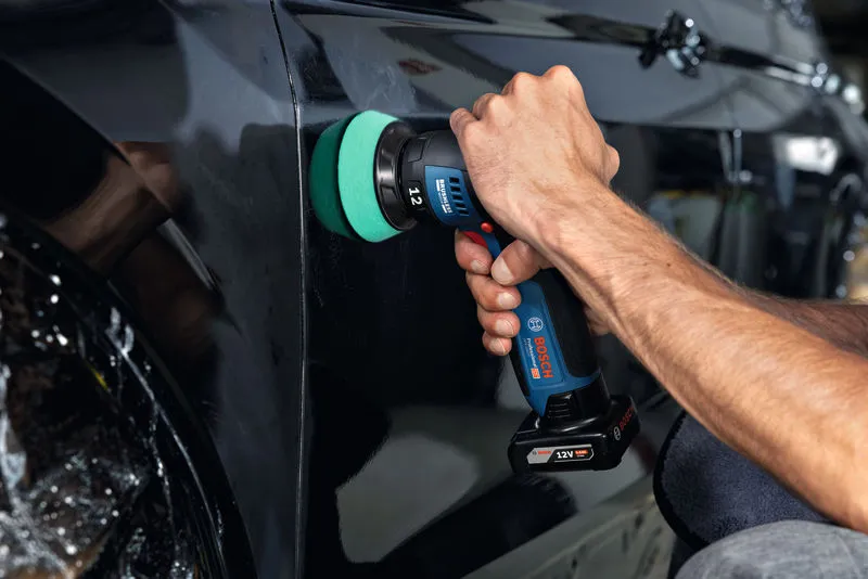Una persona pule la puerta de un coche negro utilizando una pulidora inalámbrica.