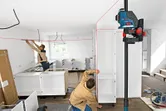 Dos personas alinean los armarios de una habitación utilizando un nivel láser.