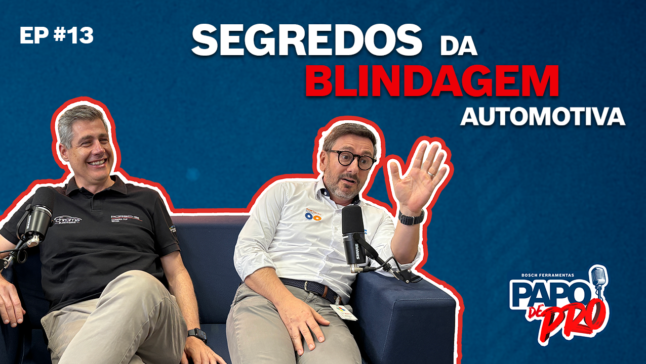 Dois homens sentados em um sofá discutindo tópicos automotivos, sorrindo.