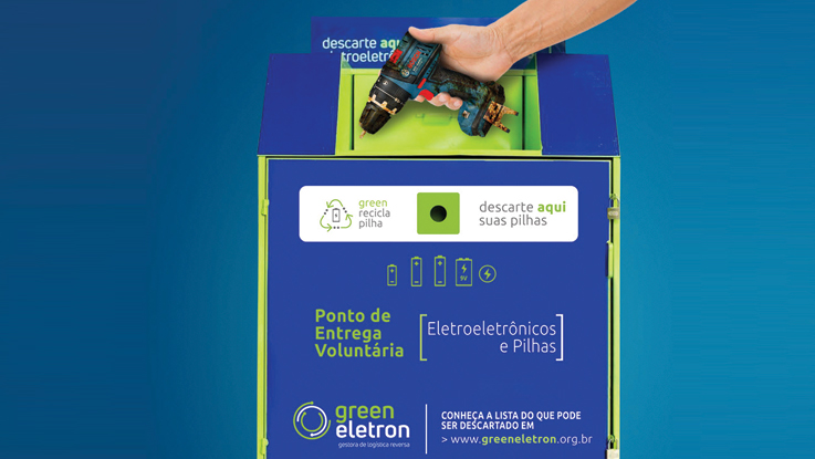 Uma mão coloca uma furadeira Bosch em uma lixeira verde para reciclagem de baterias.