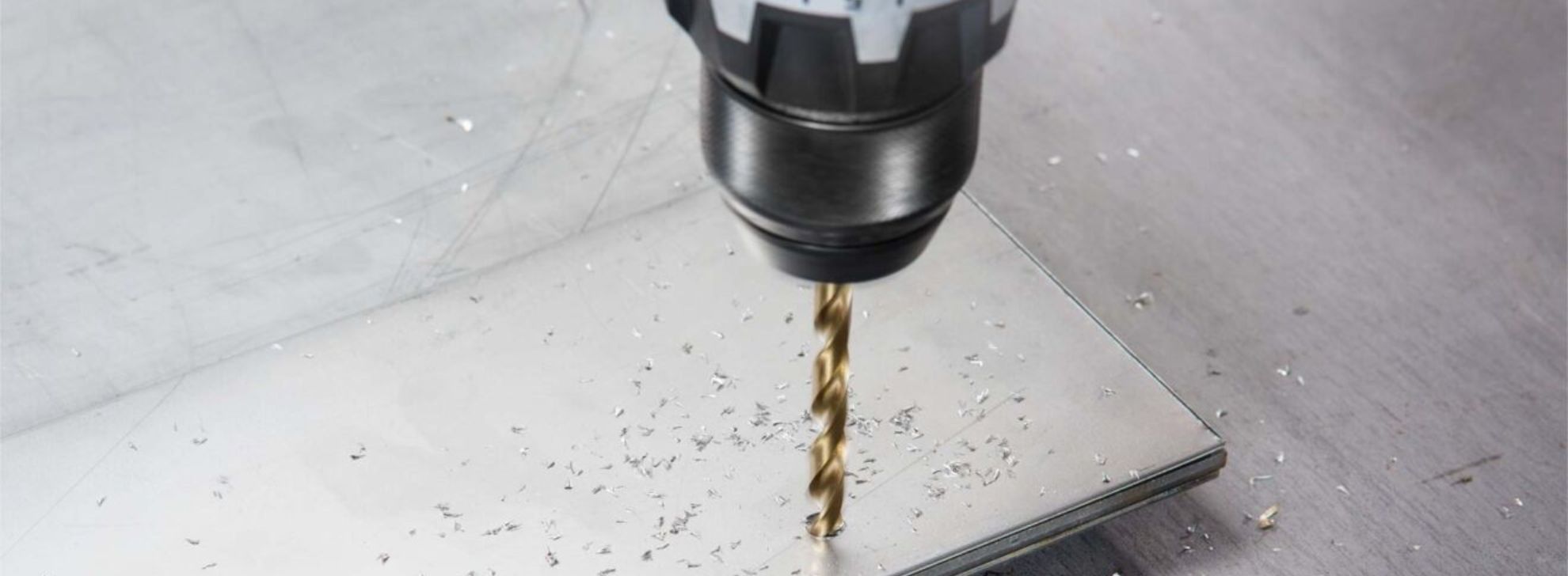 Uma furadeira Bosch Professional está perfurando uma chapa de metal, com aparas visíveis.