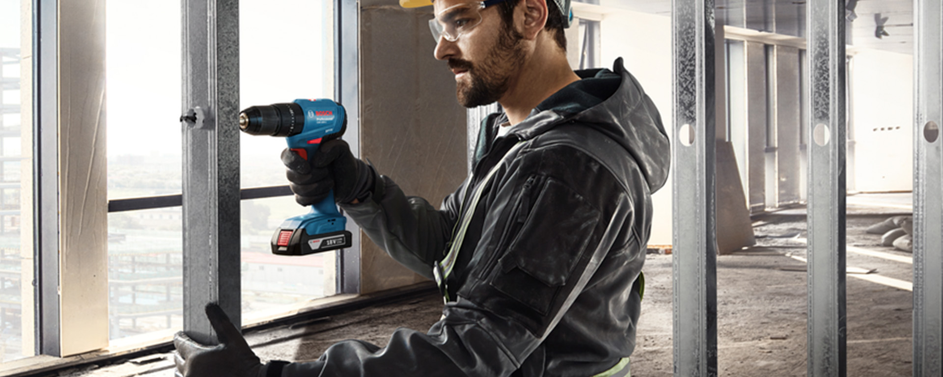 Um homem usa uma furadeira azul Bosch Professional em um canteiro de obras.
