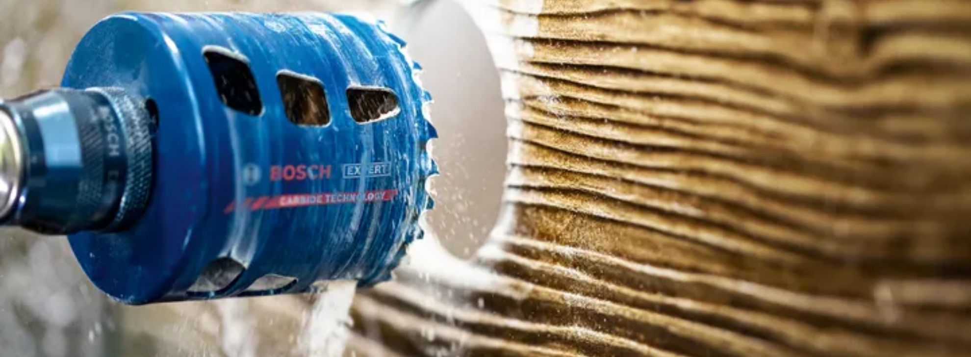 Uma serra copo azul da Bosch Professional corta madeira texturizada.