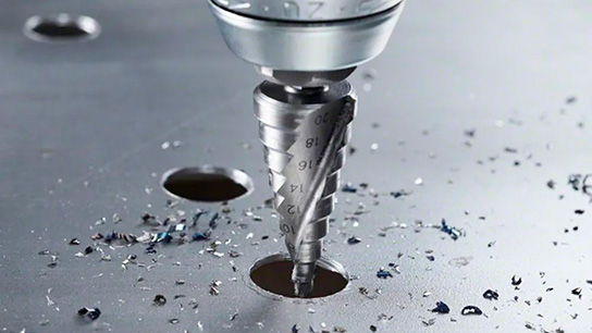 Uma broca profissional da Bosch está perfurando uma superfície metálica, com aparas espalhadas.