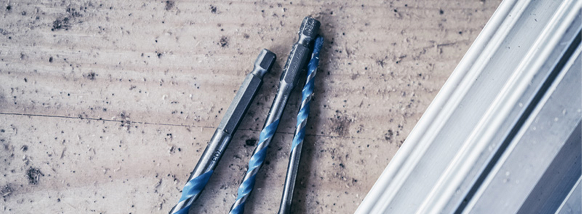 Três brocas Bosch Professional sobre uma superfície de madeira.