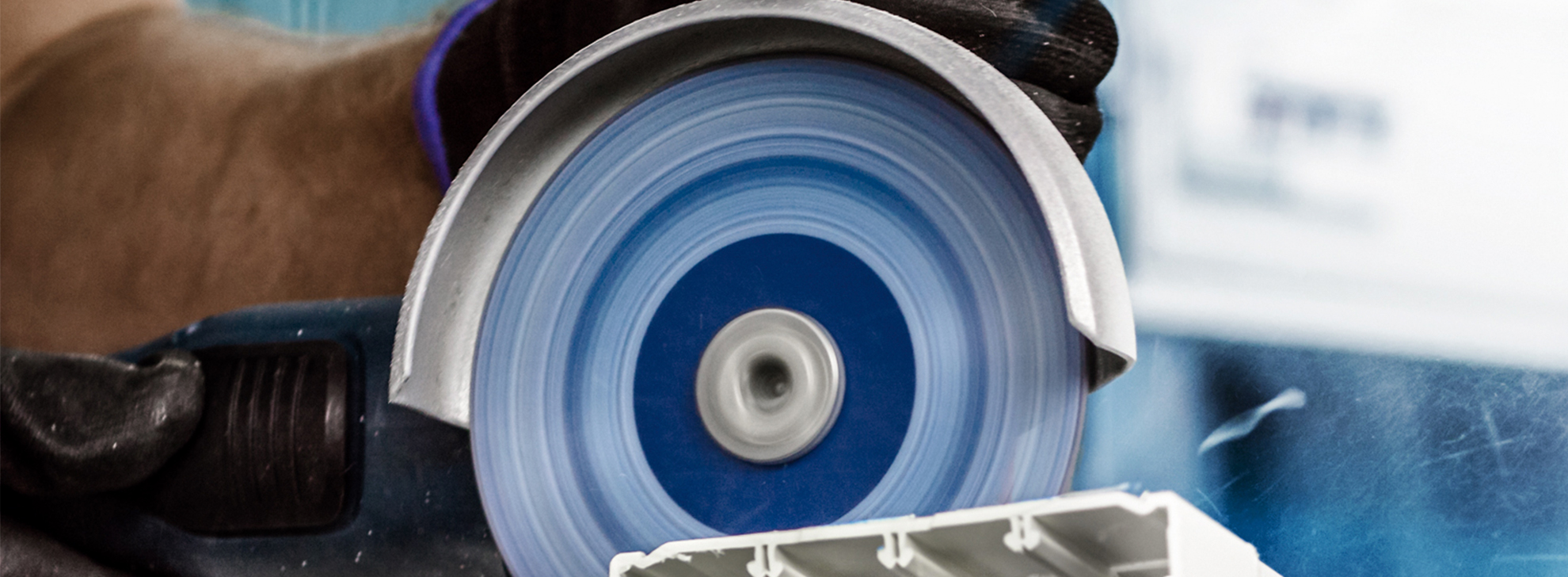 Uma serra circular profissional Bosch corta um pedaço de perfil branco.