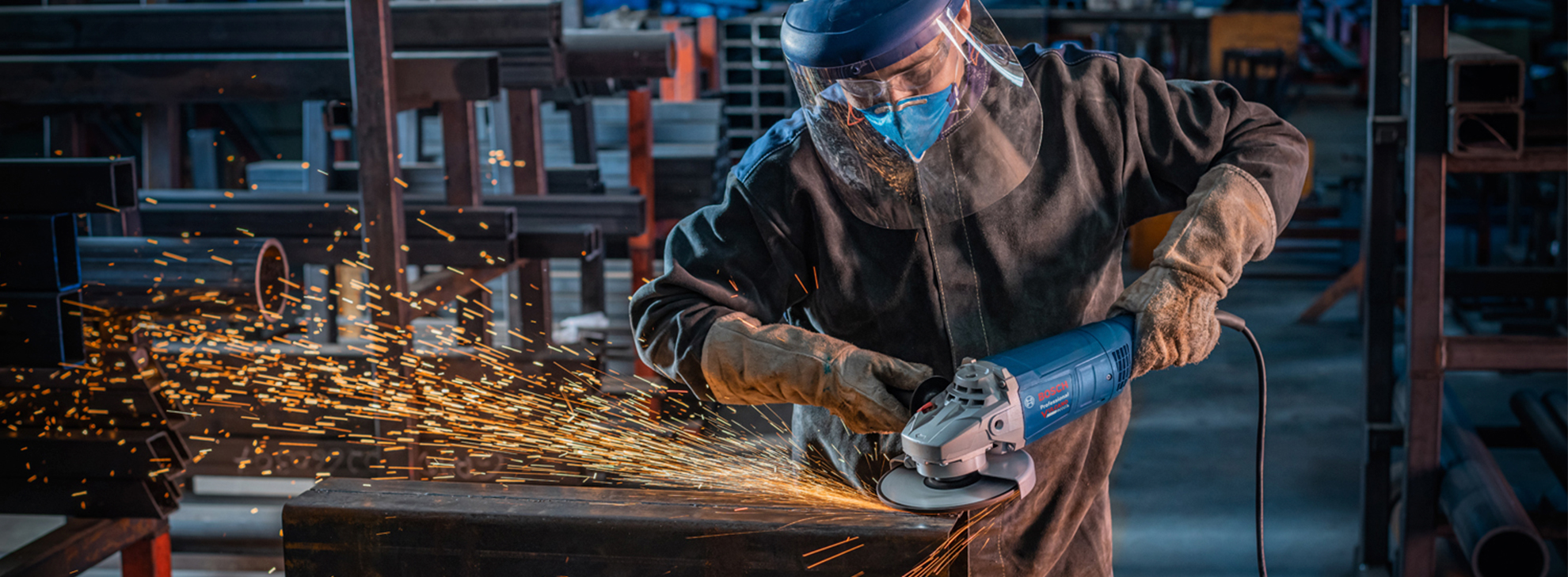 Um trabalhador com equipamento de segurança usa um moedor Bosch, criando faíscas dentro de casa.