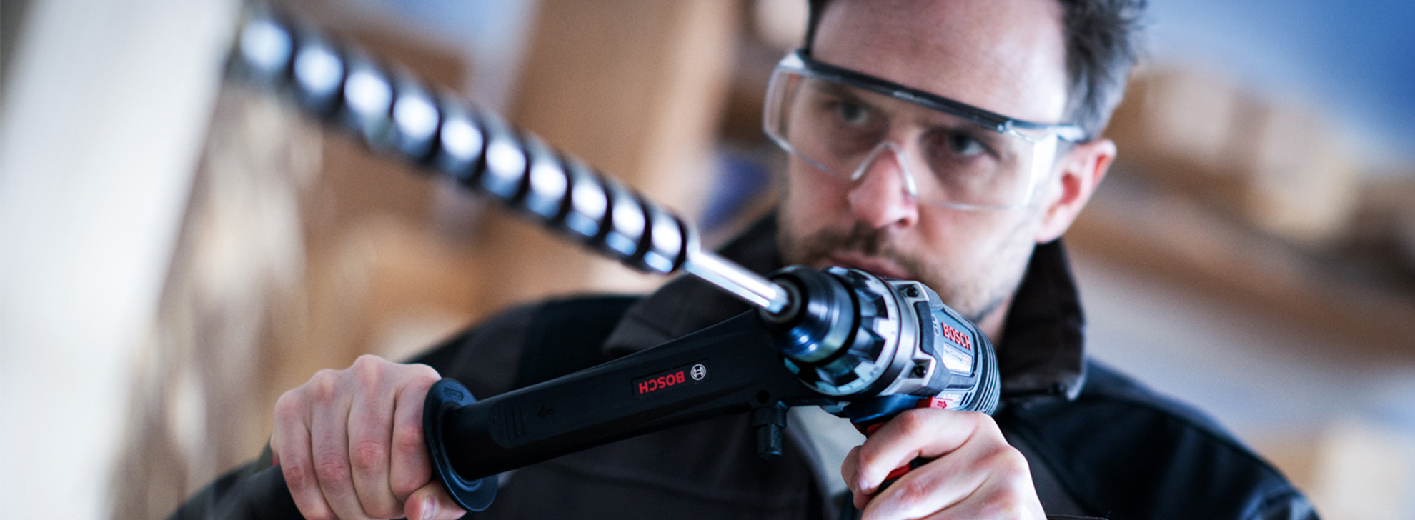 Um homem com óculos de segurança usa uma ferramenta Bosch Professional em uma oficina.