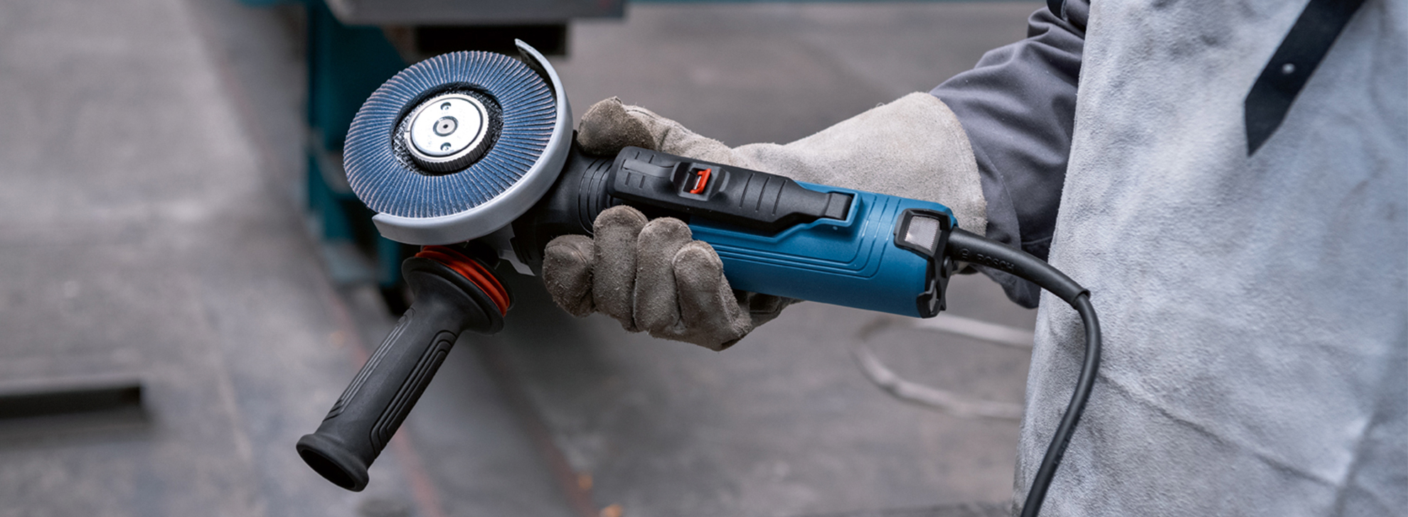 Uma esmerilhadeira angular Bosch Professional é segurada por uma pessoa com luvas.