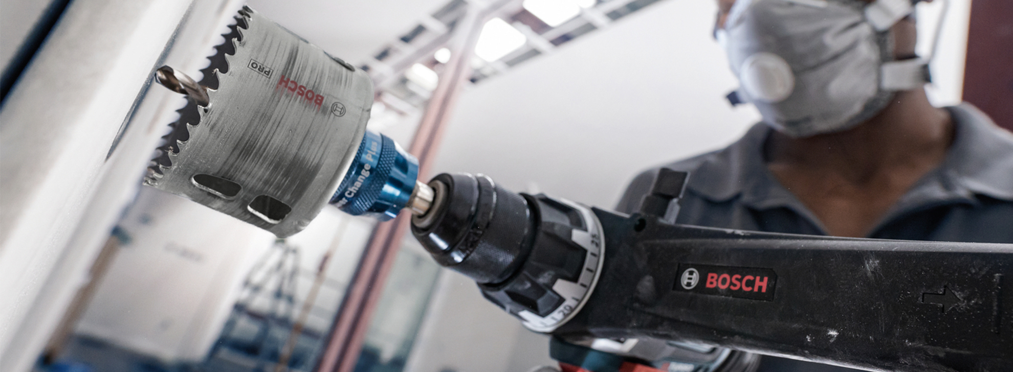 Uma furadeira Bosch Professional com uma serra copo é usada em uma parede.