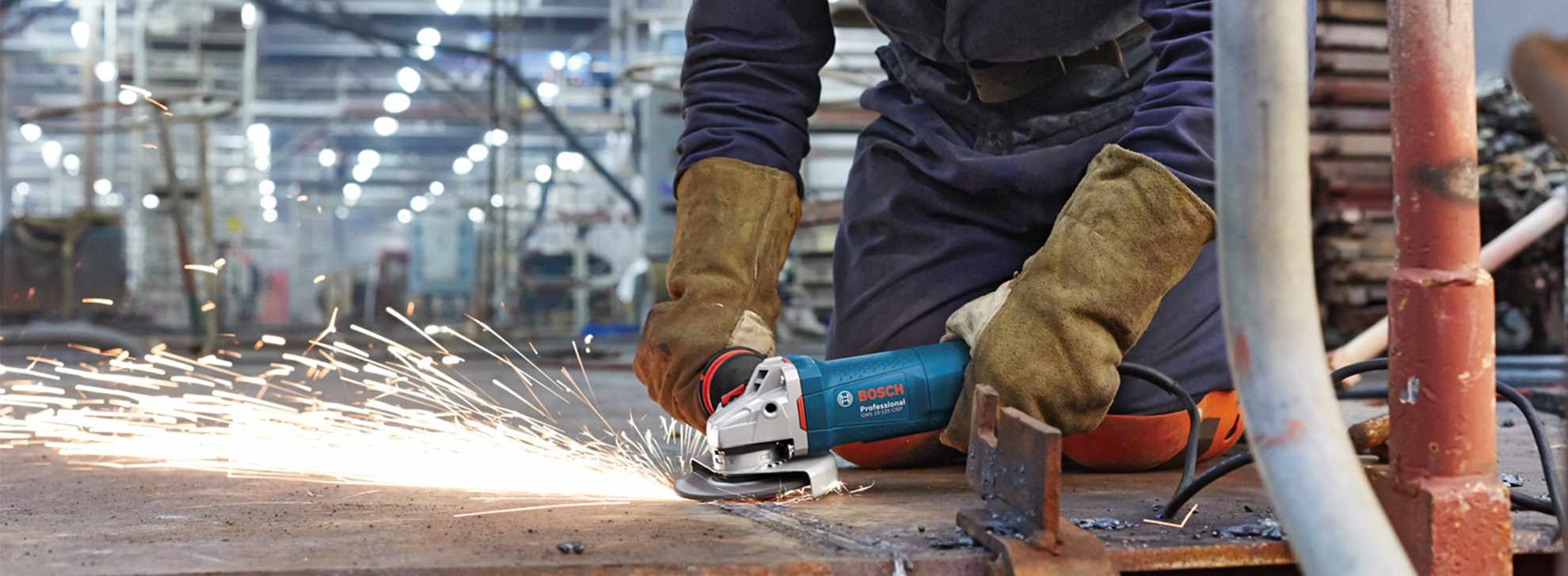 Um cortador de ângulo Bosch Professional faísca ao cortar metal no chão da oficina.