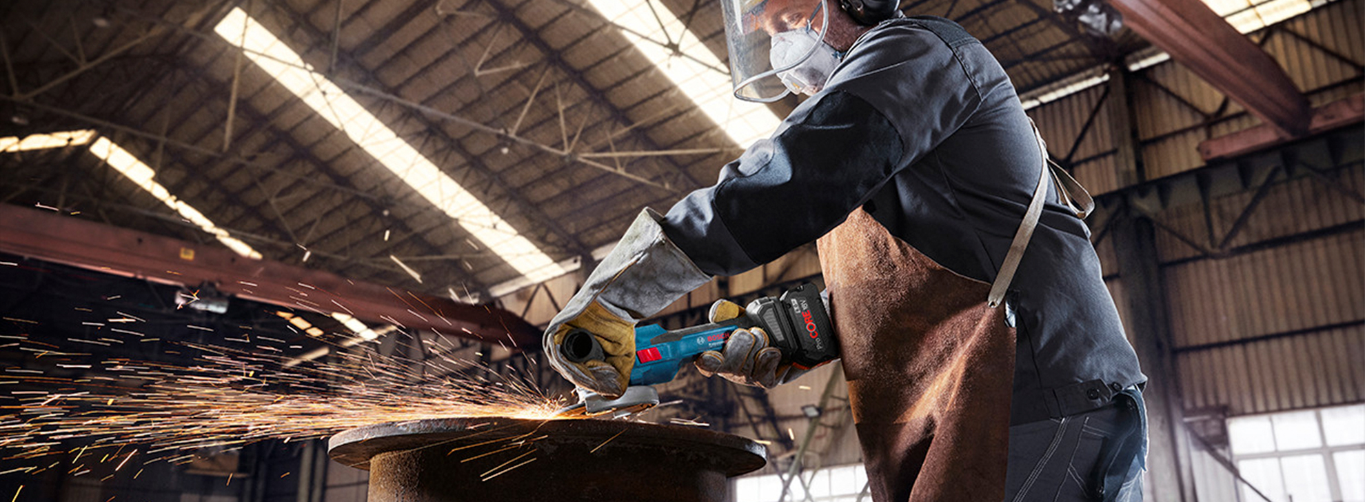Um trabalhador em uma oficina usa uma esmerilhadeira angular Bosch Professional, criando faíscas.
