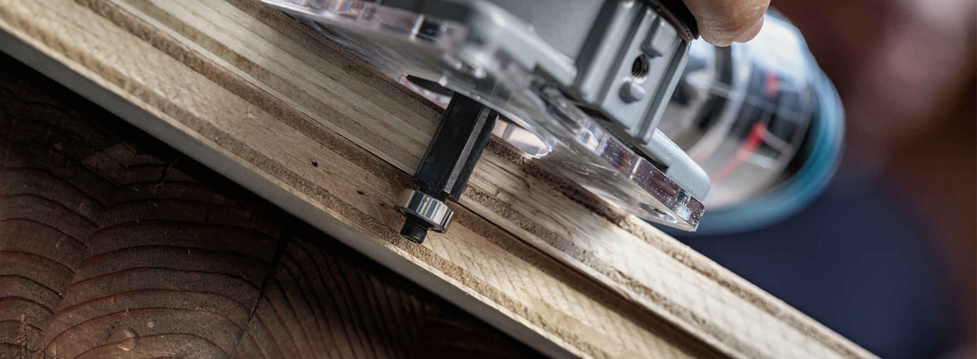 Um roteador profissional da Bosch é utilizado em uma superfície de madeira, com foco na precisão.