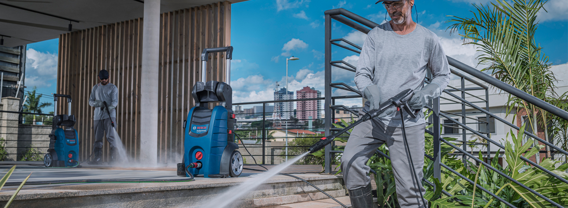 Dois homens usam lavadoras de alta pressão Bosch Professional ao ar livre, limpando superfícies.