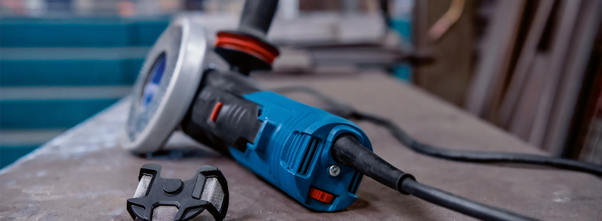 Uma esmerilhadeira angular azul da Bosch Professional repousa em uma bancada de trabalho com um acessório de ferramenta.