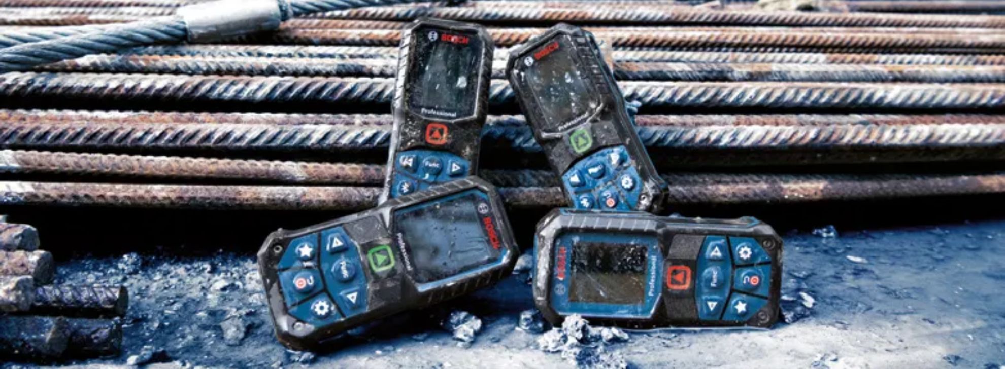 Quatro ferramentas Bosch Professional em um canteiro de obras com barras de metal enferrujadas.