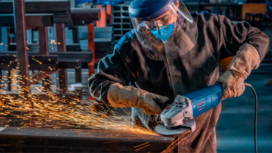 Um trabalhador com equipamento de proteção utiliza um moedor Bosch, criando faíscas.