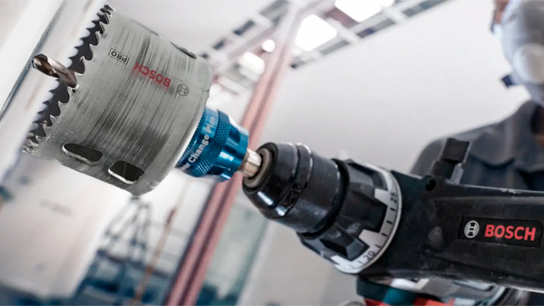 Uma furadeira Bosch Professional com um acessório de serra copo em uso.