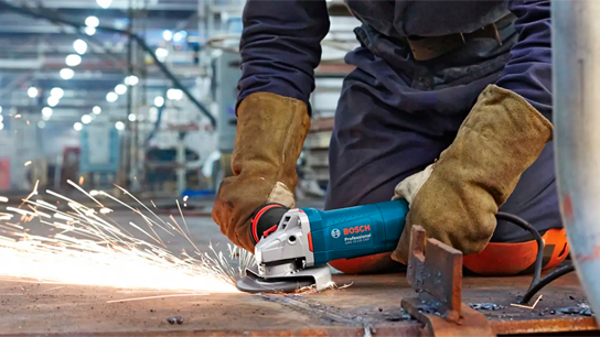 Uma pessoa usando uma esmerilhadeira angular Bosch Professional, criando faíscas.