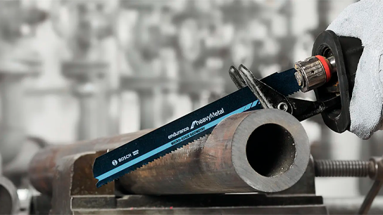 Uma serra Bosch Professional está cortando um tubo de metal em uma oficina.