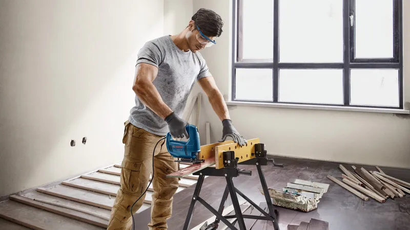 Homem cortando madeira em ambiente fechado.