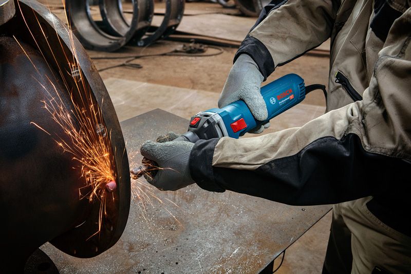 Uma pessoa usando equipamento de segurança tritura metal, criando faíscas brilhantes.