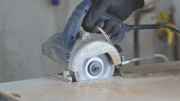 Uma pessoa usando equipamento de segurança opera uma serra circular para cortar uma laje.