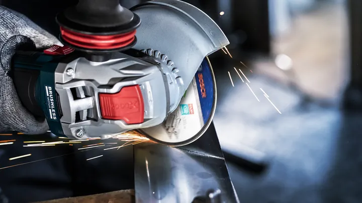 Uma pessoa usando equipamento de segurança tritura metal, criando faíscas brilhantes.