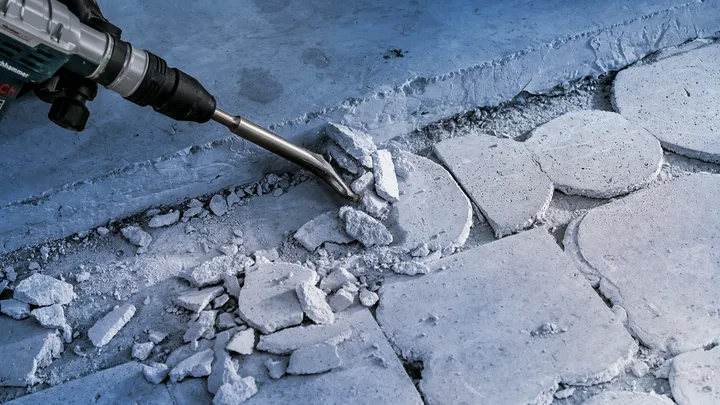 Ferramenta de demolição quebrando ladrilhos de concreto em um canteiro de obras.