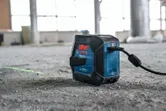 Ferramenta de nivelamento a laser projeta uma linha verde em um piso de concreto empoeirado.